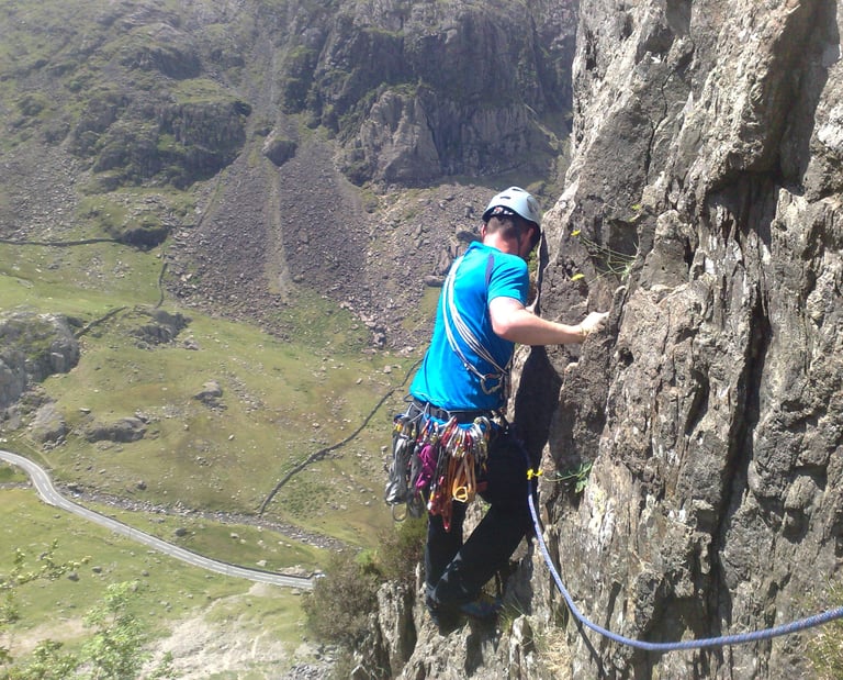 climber high on a rockface, traversing