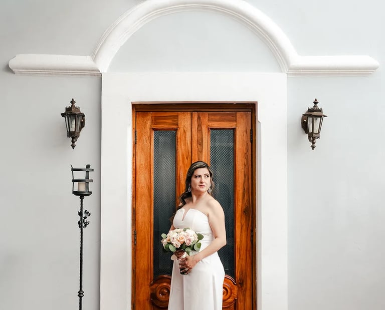 Novia en el día de su boda posando elegante con su ramo de flores en el centro histórico de Quito