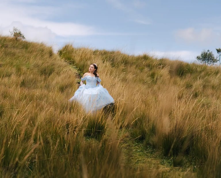 Fotografía de quinceañera con vestido celeste de princesa caminando por el prado amarillo en Quito
