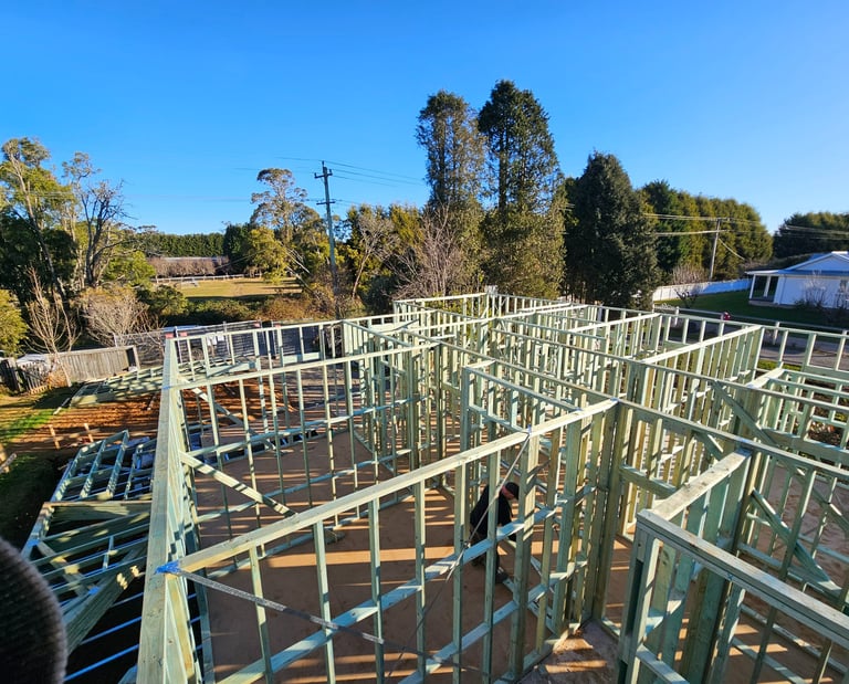 Overhead view of a new residential house construction featuring green timber wall framing.