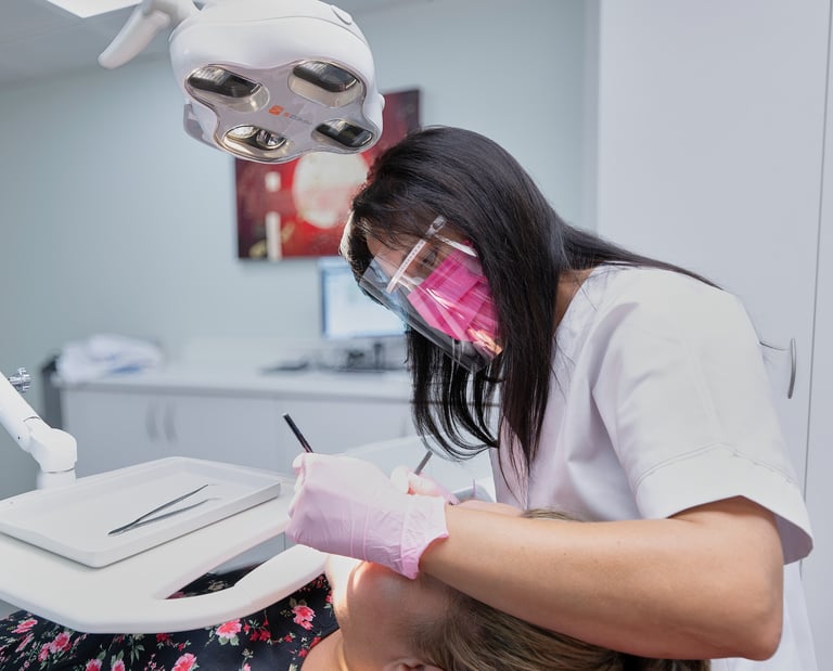 Un dentiste portant une visière de protection réalise un soin dentaire