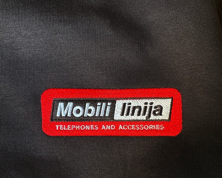 Embroidered Mobili linija logo on a black sweatshirt for telephones and accessories branding. 