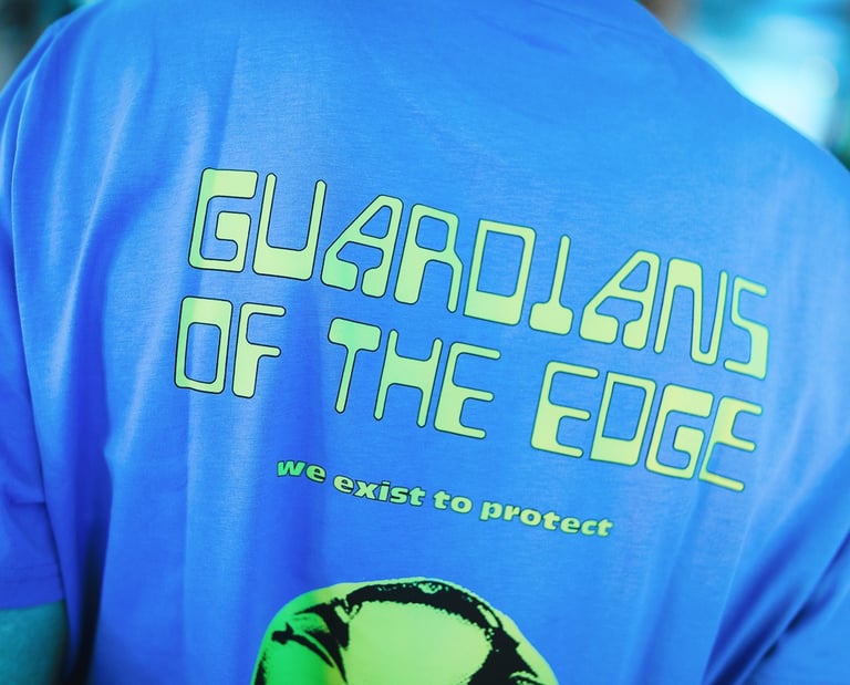 Back of a blue t-shirt with Guardians of the Edge text in a lime green graphic font.