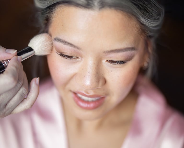 Une mariée qui sourit se fait maquiller pendant son essai.