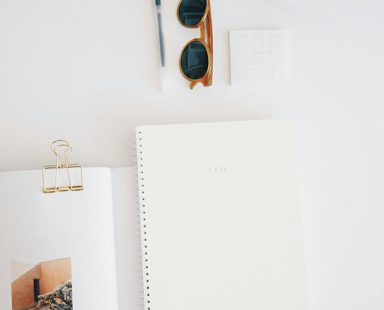 dessus de bureau blanc avec carnet, crayon, tasse de café. Un décor tout en simplicité