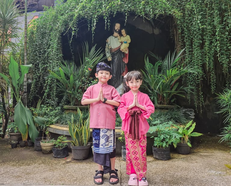 Two children in traditional pink Balinese clothing posing.