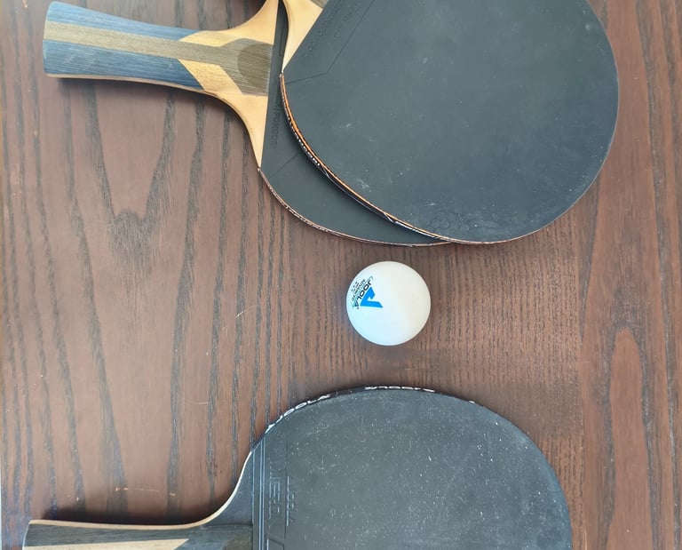 Review de raquetes de ping-pong JOOLA Carbon com revestimento preto e bola branca.