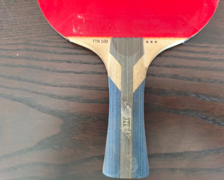 Review de raquete ping pong JOOLA TTM 200 detalhando o acabamento do cabo de madeira de 3 estrelas.