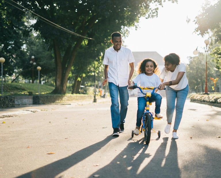 family helping child ride a bike