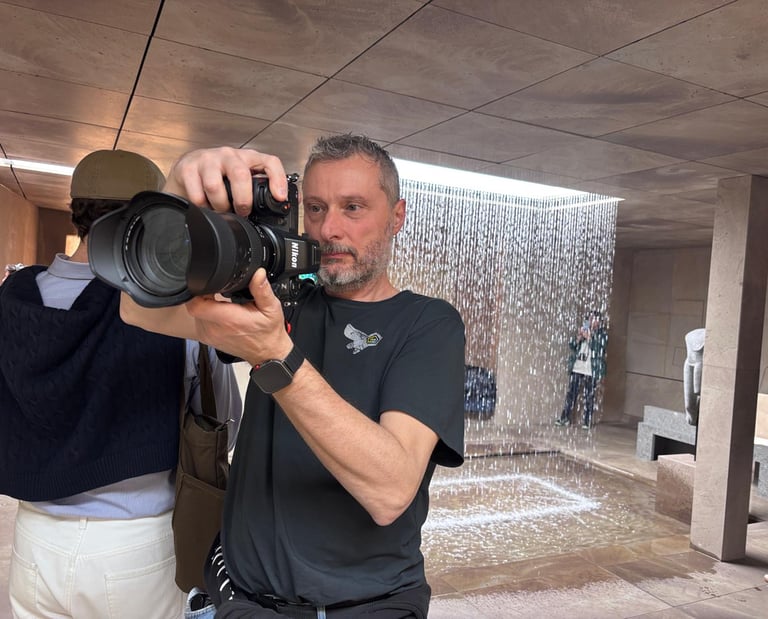 Professional photographer using a Nikon mirrorless camera to capture an indoor waterfall installation.