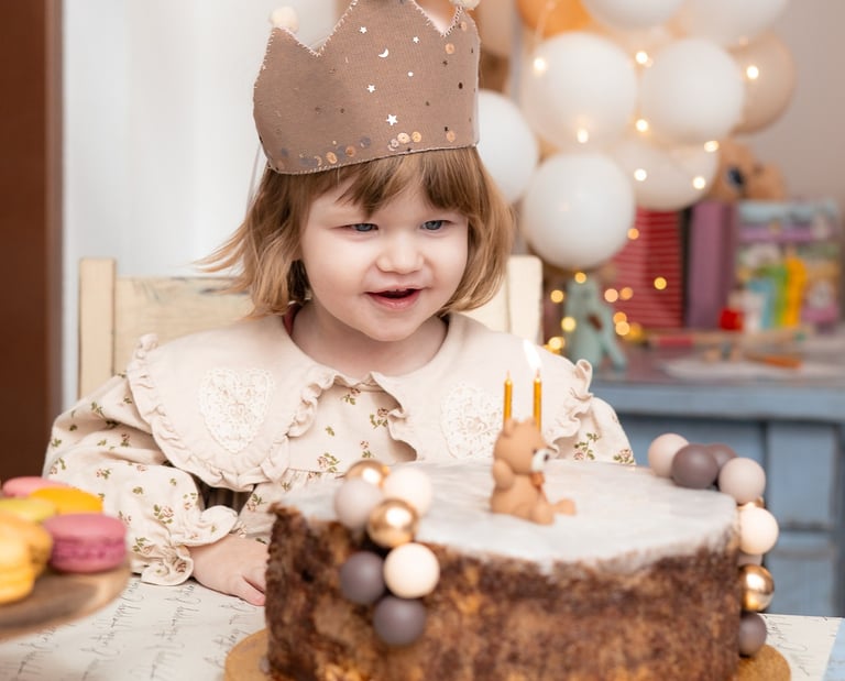 mala djevojčica sjedi za stolom i puše svijeće na torti