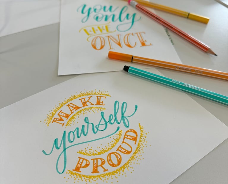 Hand-drawn lettering art on cards with motivational quotes and colorful pens on a desk.