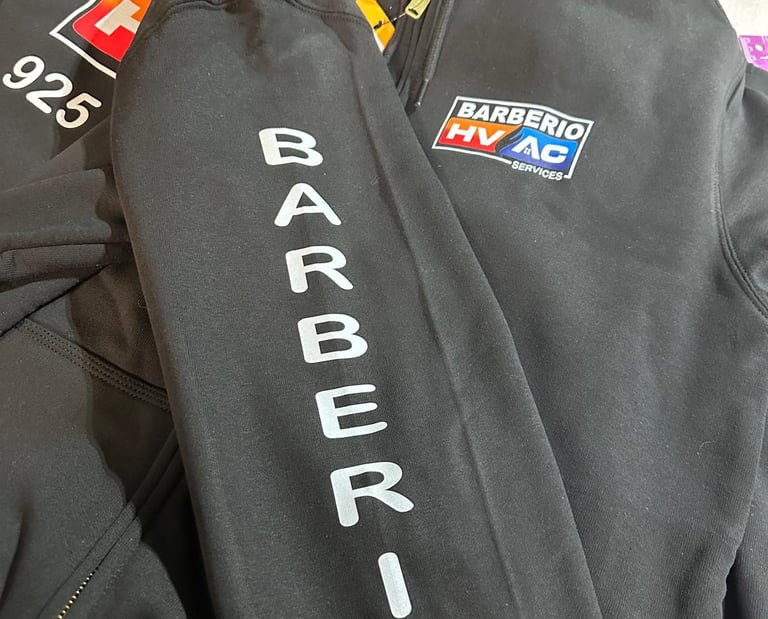Custom black Barberio HVAC services zip-up hoodie with sleeve printing and company logo.
