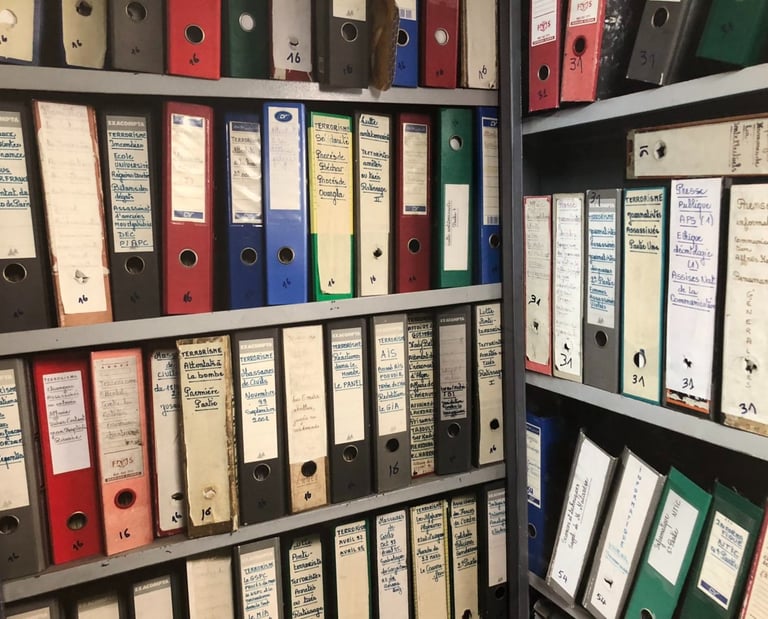 Rows of colorful lever arch ring binder folders on shelves containing organized archive documents and 