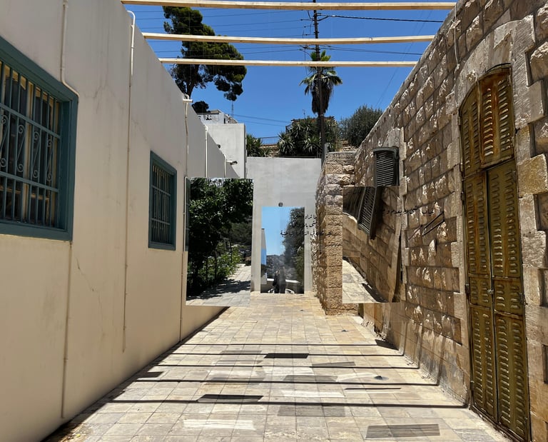 Outdoor art installation with large mirrors in a stone alleyway named luminous space.