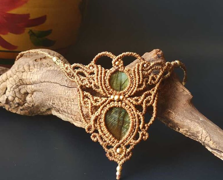 Collar de macramé hecho a mano con piedras de labradorita verde sobre un trozo de madera