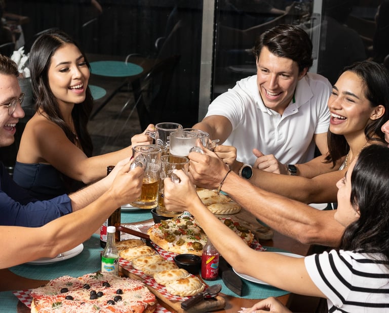 Fotografía de estilo de vida en Cancún. Grupo de amigos brindando con cerveza en restaurante.