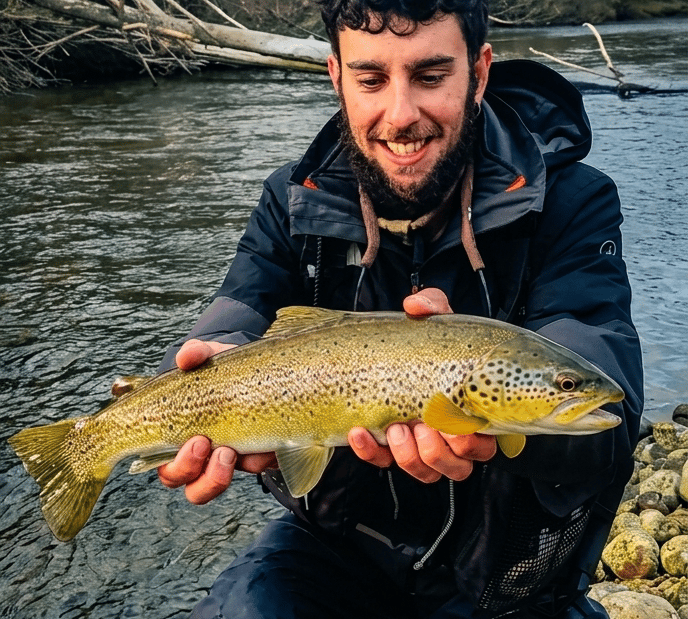 Guía de pesca con trucha en la mano pescada en el río Porma en León