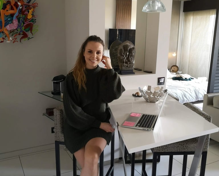 Christine Hauser, RTT Practitioner, sitting at a table with a laptop in a stylish home setting
