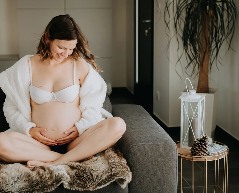 une femme enceinte assise sur son canapé 