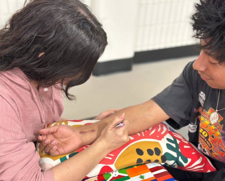 young woman applying henna to forearm of smiling young man