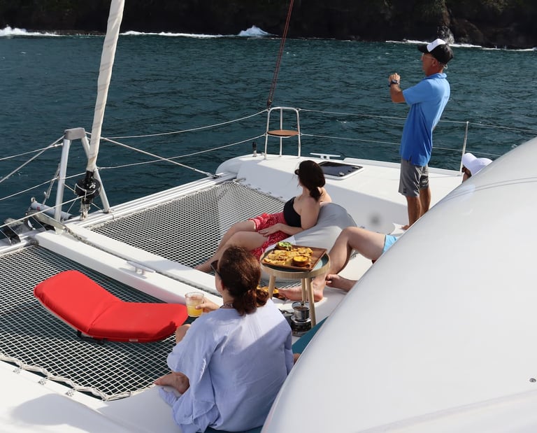 Guests relaxing on deck while crew guides catamaran through Gulf of Papagayo