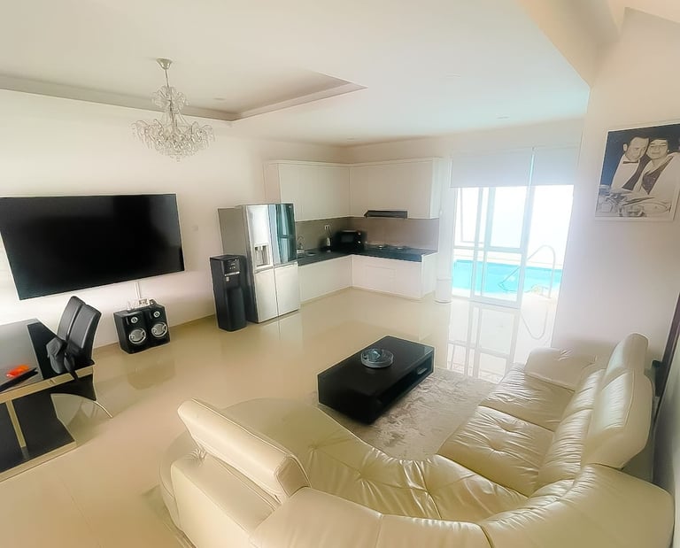 Modern living room at Villa Sattara Seminyak with leather sofa, 85-inch TV and open dining area