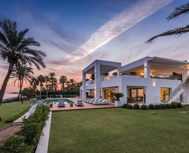 Contemporary beachfront villa at sunset with infinity pool and palm lined gardens