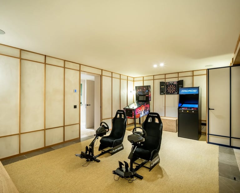 Game room at Villa La Gratitud with racing simulators, arcade machines, and darts