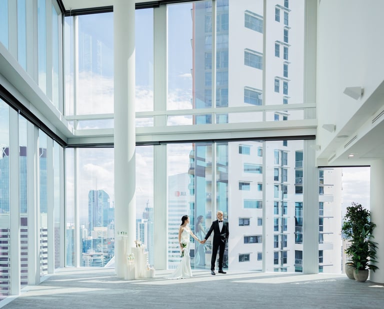 a bride and groom standing in a large room with a view of the city