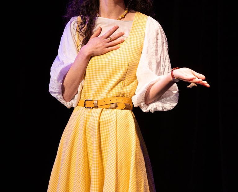 Aude Fy dans une pièce de théâtre sur scène en robe jaune