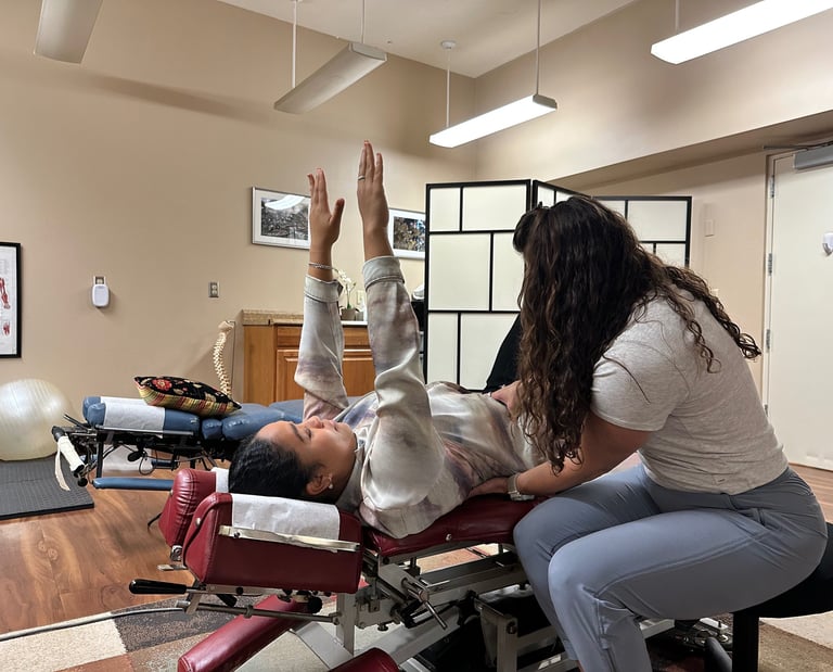 Chiropractor with hands on patients stomach and lower back, coaching form for rehab exercise.