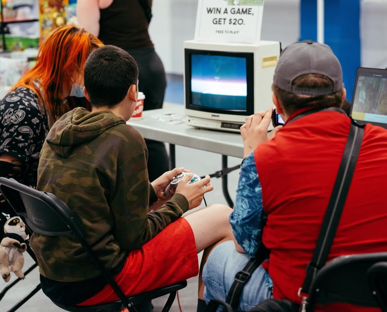 Close up image of two people sitting at an old tv playing some video games together at the event.