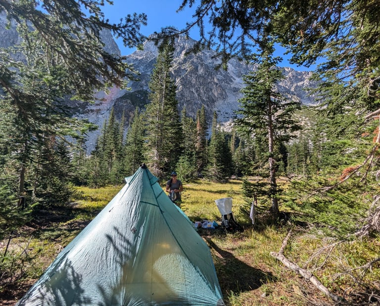 A hiker at a mountain campsite with a Hyperlite Ultamid 2 tent in the Alpine Lake Wilderness.