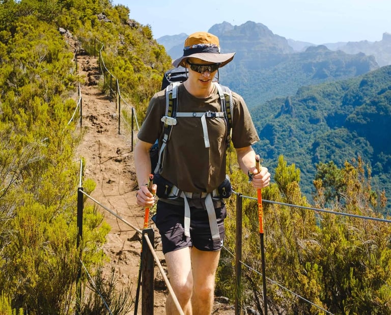 Wanderer mit Rucksack und Stöcken auf einem schmalen Bergpfad. Outdoor-Foto von Joel Pingel.