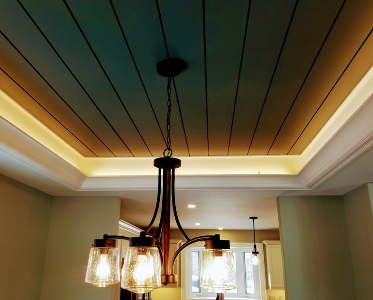 Elegant bronze chandelier with seeded glass shades hanging from a coffered shiplap ceiling with cove lighting.