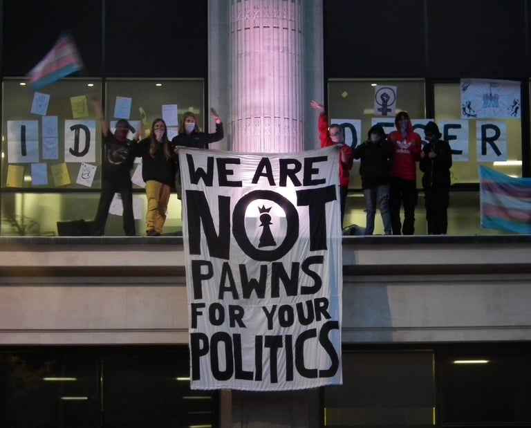 Activists standing on top of NHS England offices with a banner "we are not prawns for your politics"