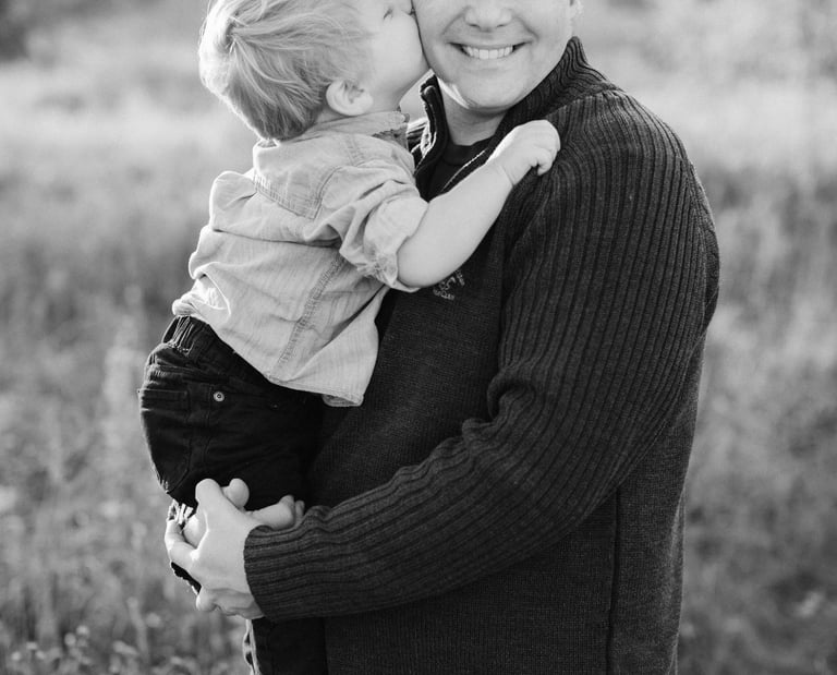 little boy kissing father on the cheek. Black and white image. 