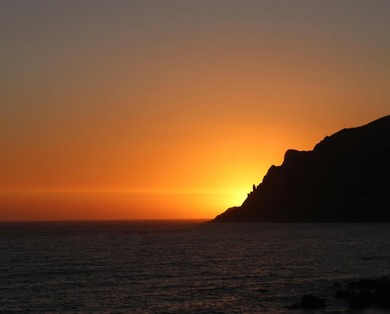 a sunset over the ocean with a boat in the water