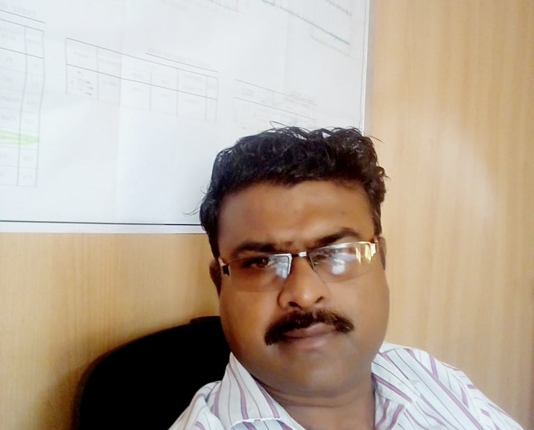a man with glasses and a mustache sitting in front of a white board