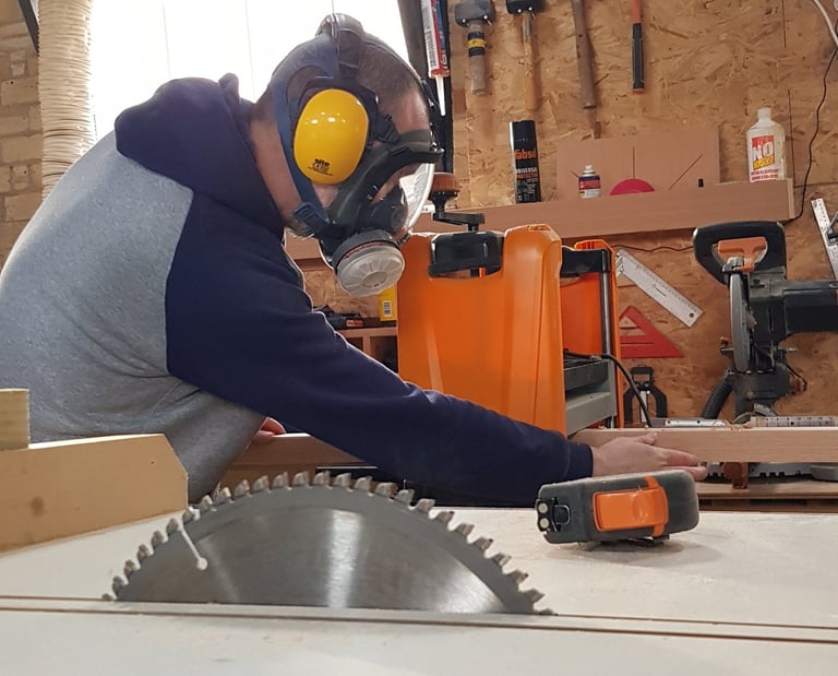 a man in a respirator mask and ear defenders in a workshop