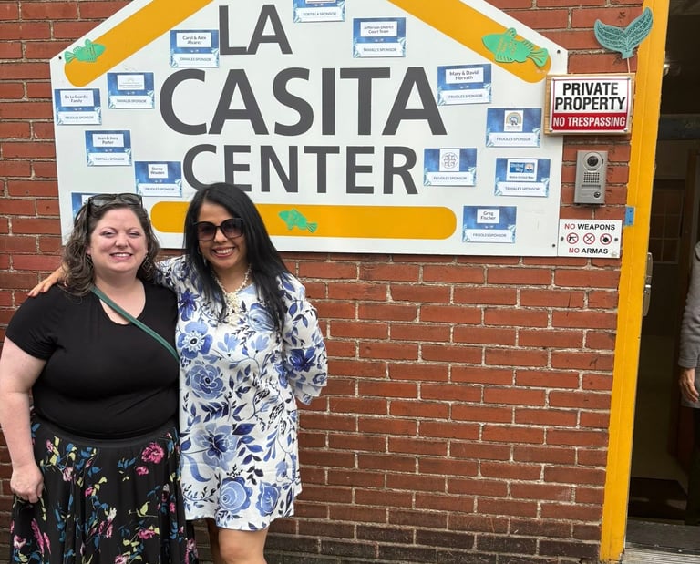 Two women standing in front of the La Casita Center building signage