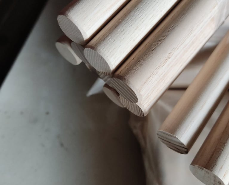 Close-up of smooth unfinished wooden dowel rods stacked for woodworking and DIY craft projects.