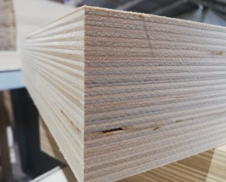 Close-up of stacked birch plywood sheets showing the layered wood grain edges for construction.