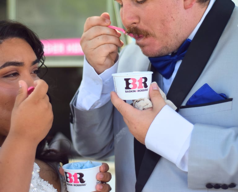Close-up of a wedding couple in a dress and gray tuxedo enjoying BR Sweet Events ice cream 