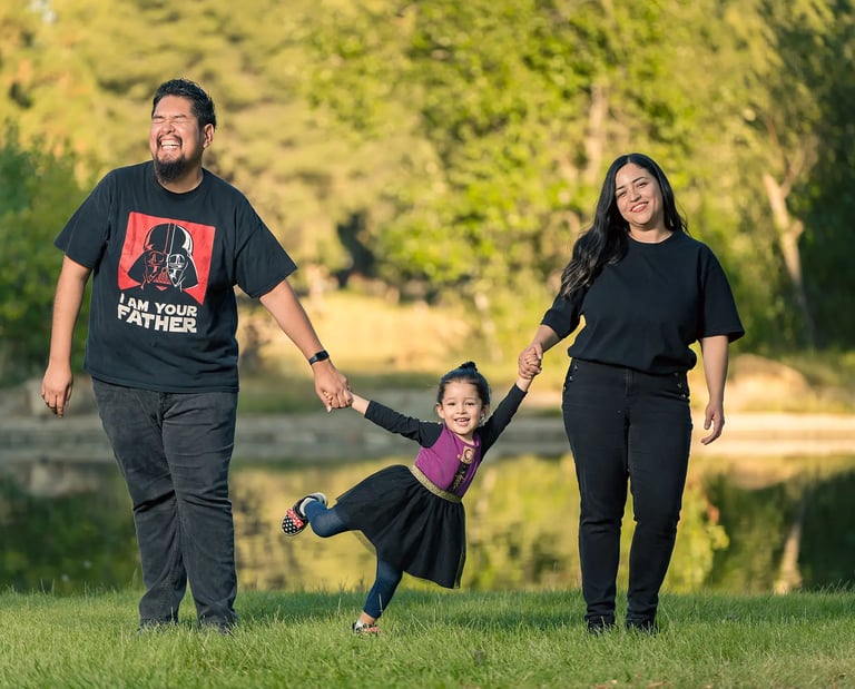 family photoshoot of a man and woman holding hands and holding kid by her hands