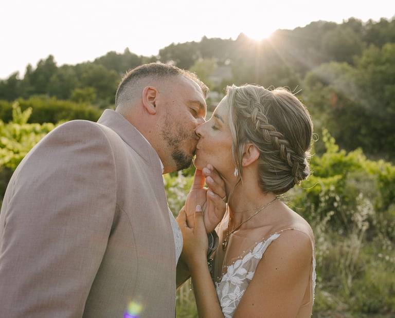 un couple jeune marié qui s'embrasse au coucher du soleil au milieu des vignes