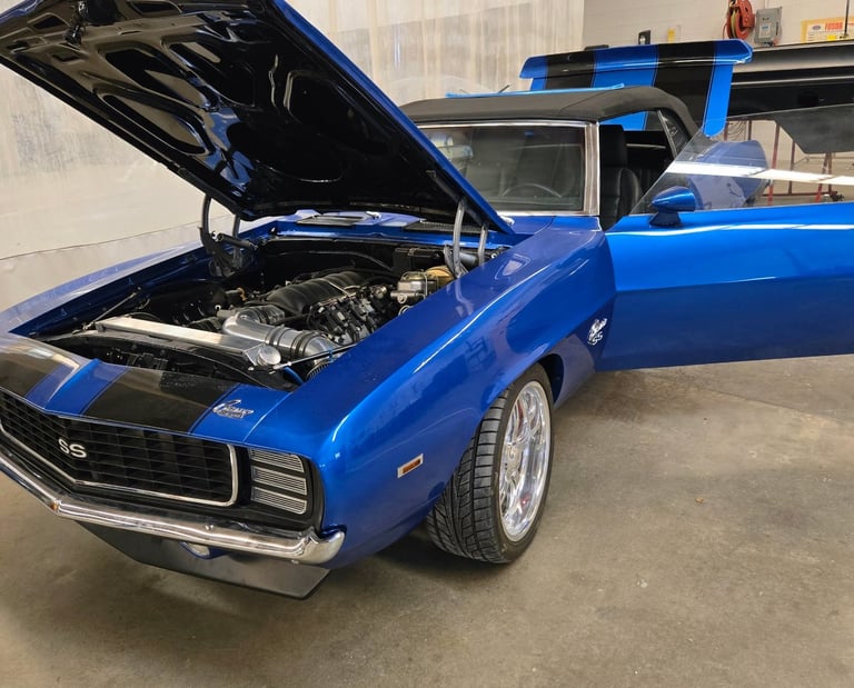 Blue classic classic muscle car with hood open inside a garage