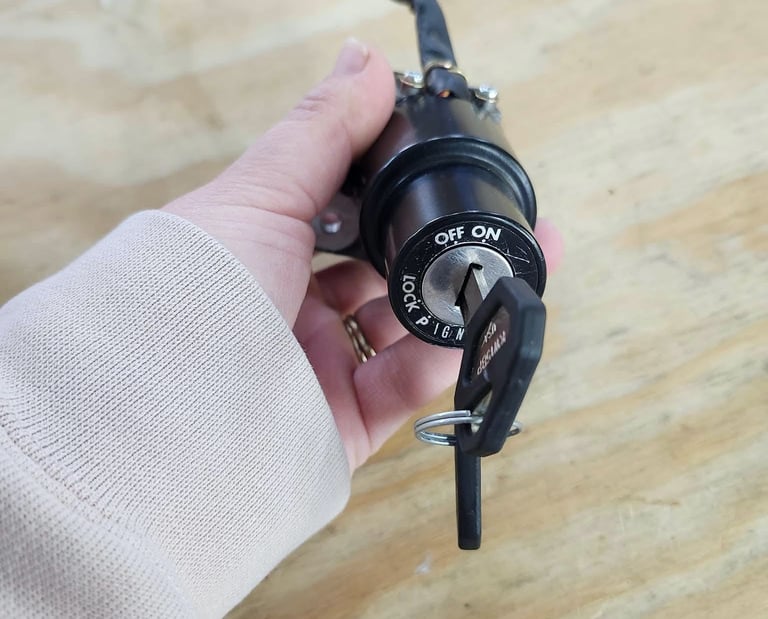 Hand holding a motorcycle ignition cylinder with key inserted