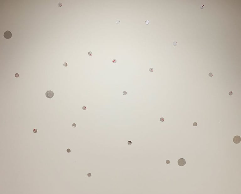 Multiple silver dot decals scattered in a playful pattern on a white background mural.